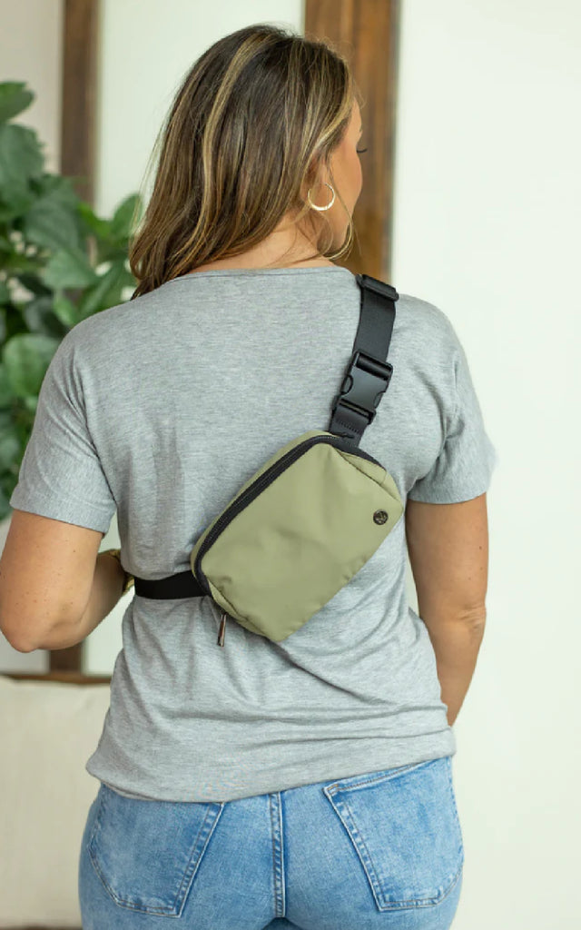 Woman wearing a bum bag in sage green across her back.