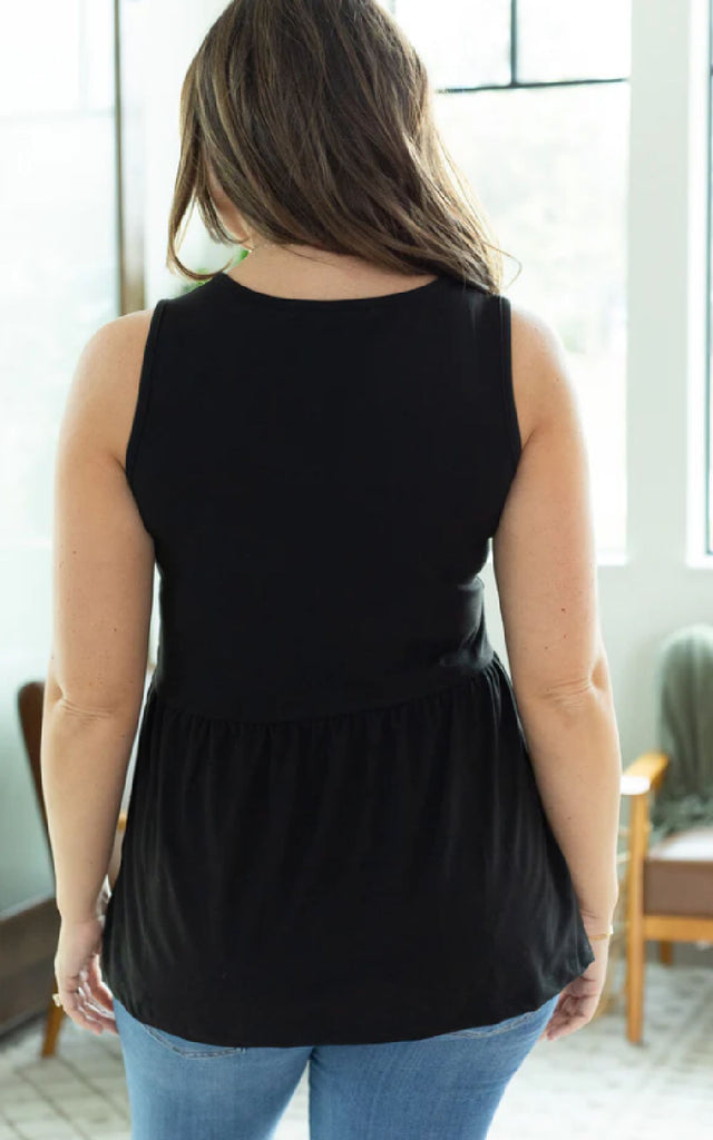 Woman wearing a black tank top with ruffles.