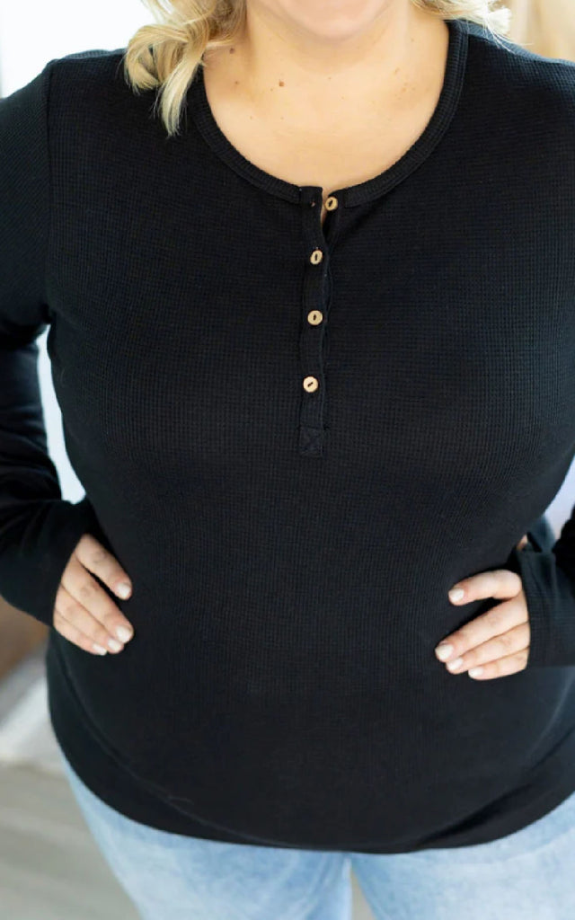 Woman wearing a long sleeve henley top with thumbholes.