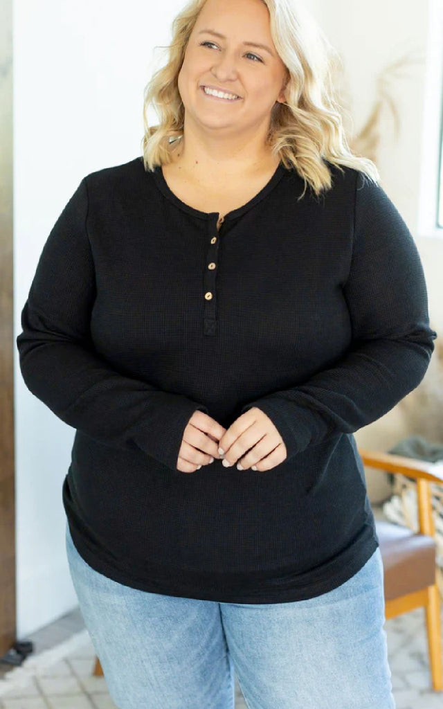 Woman wearing a long sleeve henley top with thumbholes.