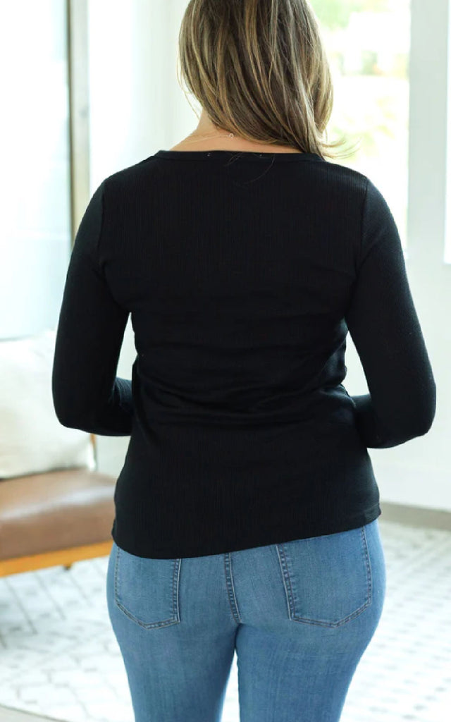 Woman wearing a long sleeve henley top with thumbholes.