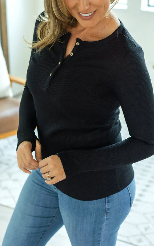 Woman wearing a long sleeve henley top with thumbholes.