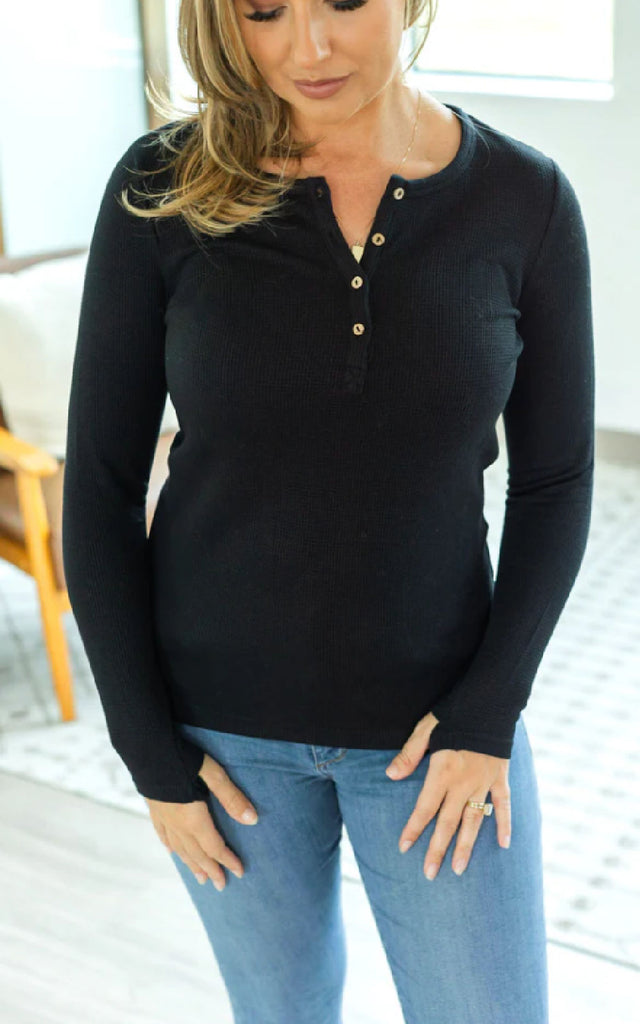 Woman wearing a long sleeve henley top with thumbholes.