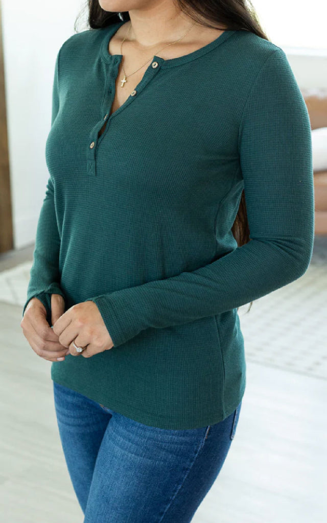 Woman wearing a long sleeve henley shirt with thumbholes.