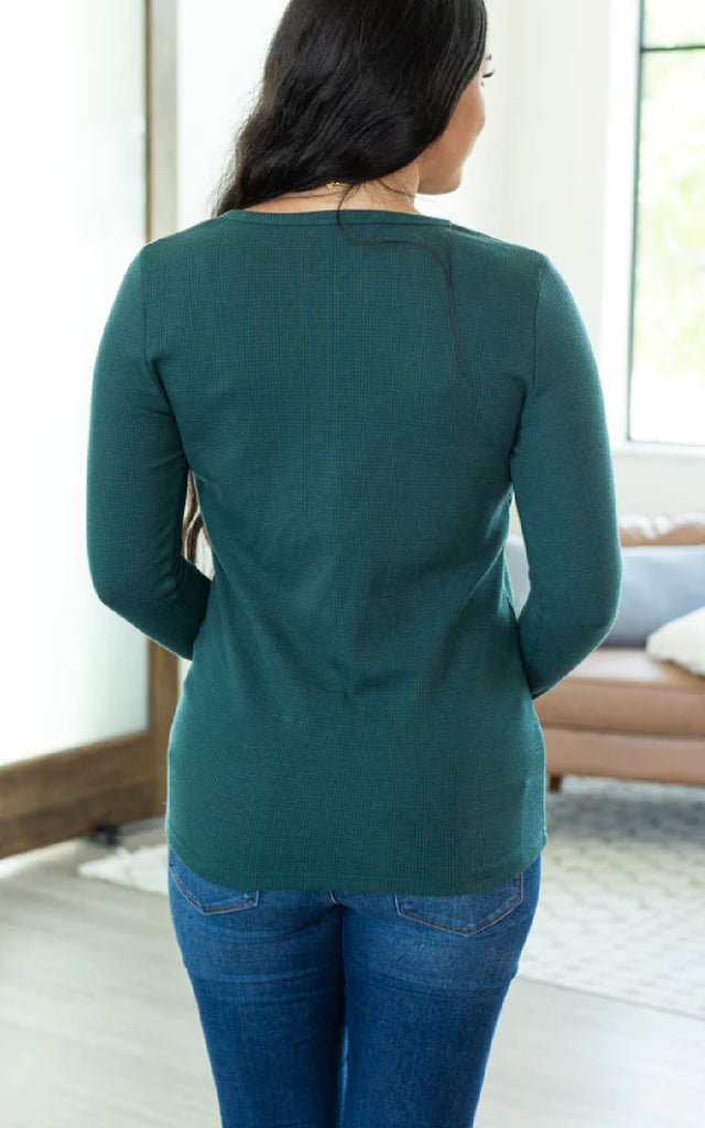 Woman wearing a long sleeve henley shirt with thumbholes.