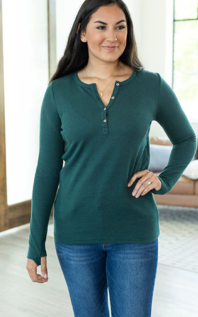 Woman wearing a long sleeve henley shirt with thumbholes.