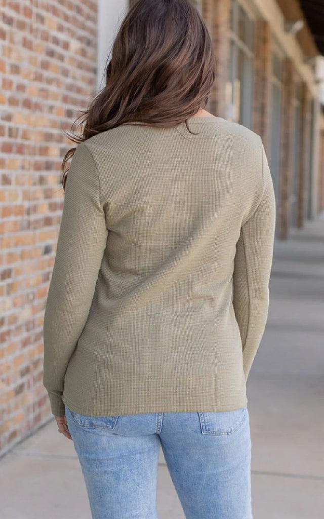 Woman wearing a long sleeve henley top with thumbholes.