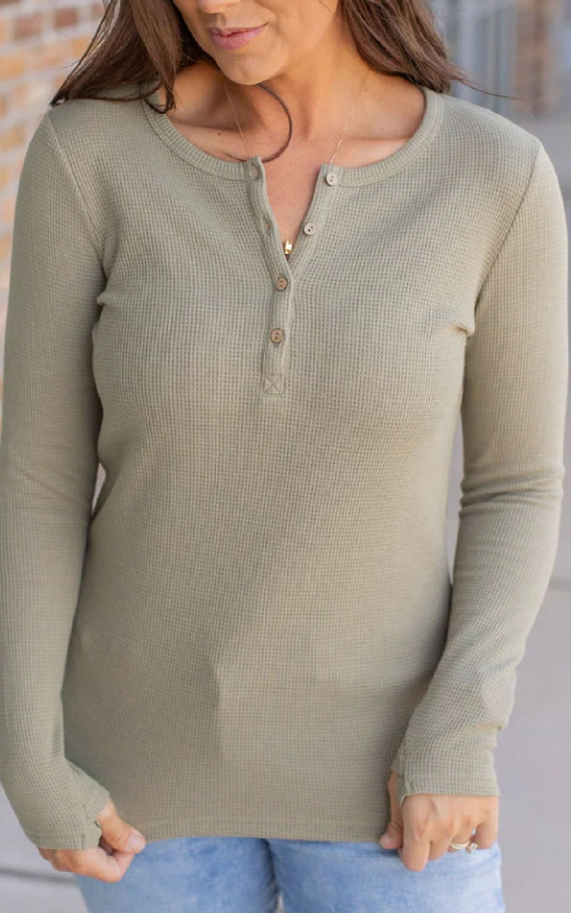 Woman wearing a long sleeve henley top with thumbholes.