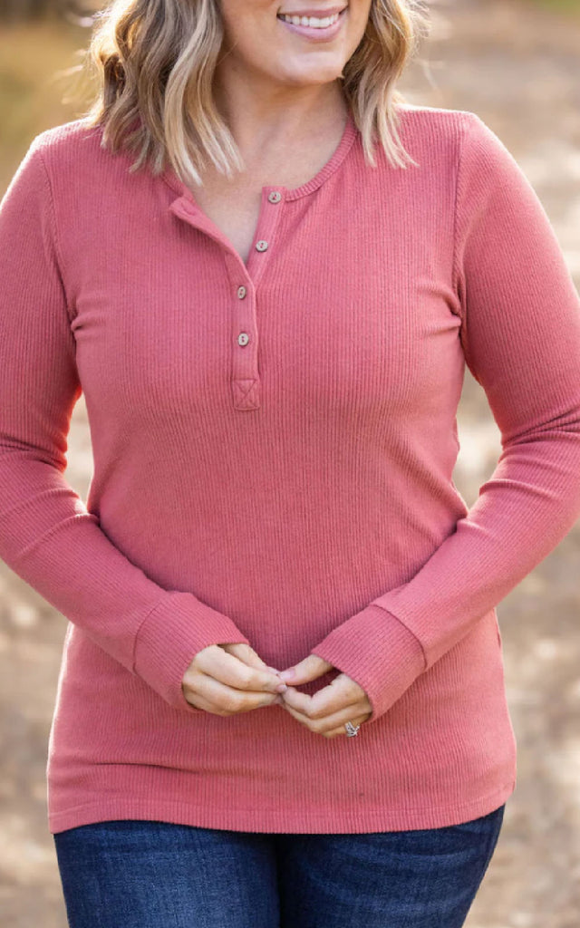 Woman posing while wearing a dark pink long sleeve henley top. 