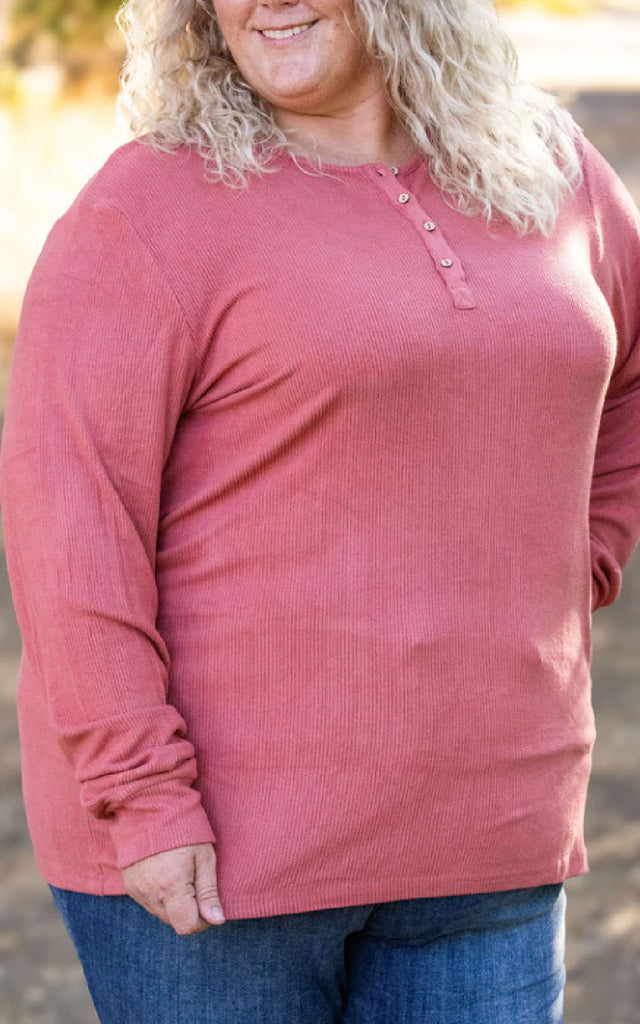 Woman posing while wearing a dark pink long sleeve henley top. 