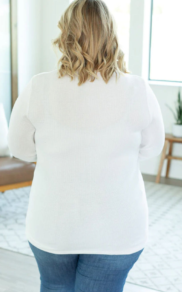 Woman wearing a white henley long sleeved shirt.